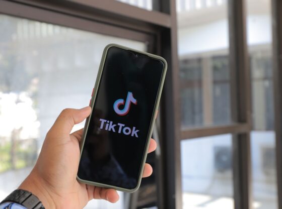Close-up of a hand holding a smartphone displaying the TikTok app indoors.